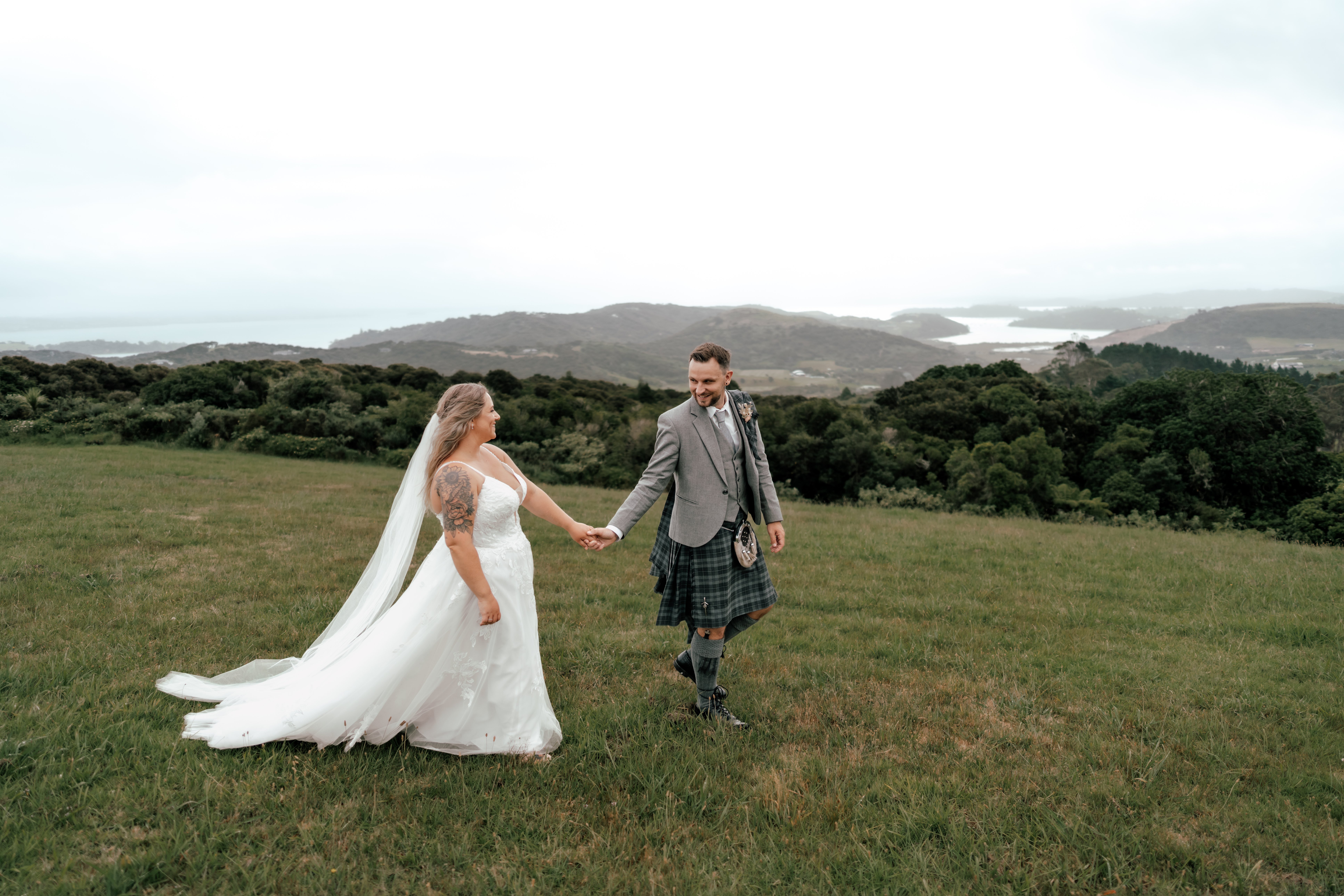 Bride and groom eloping on Waiheke Island with coastal views and groom in traditional Scottish kilt