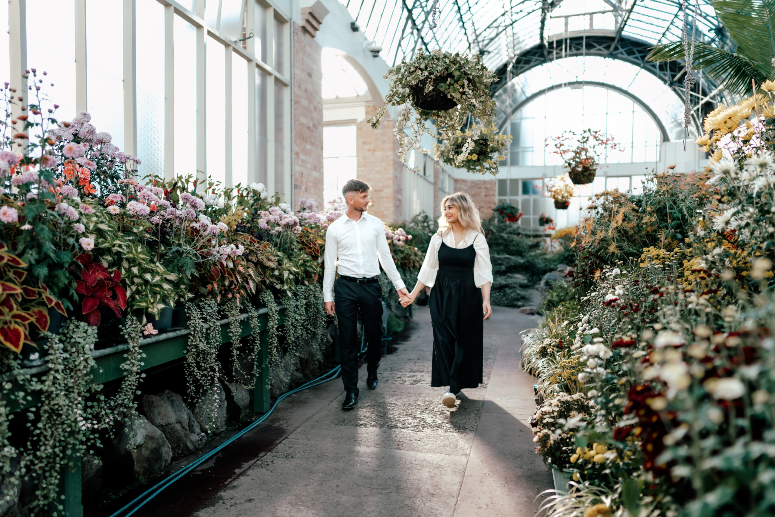 Couple celebrating their sunny Auckland proposal with romantic engagement photos at the Wintergardens surrounded by colorful flowers and greenery