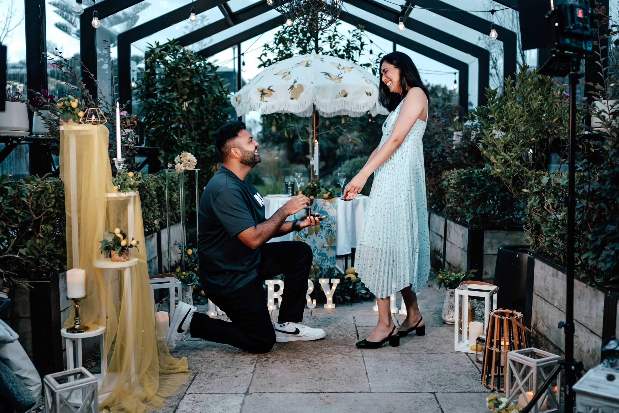 Surprise indoor proposal at The Greenhouse at The Grange in Auckland with candles, flowers, and emotional reactions