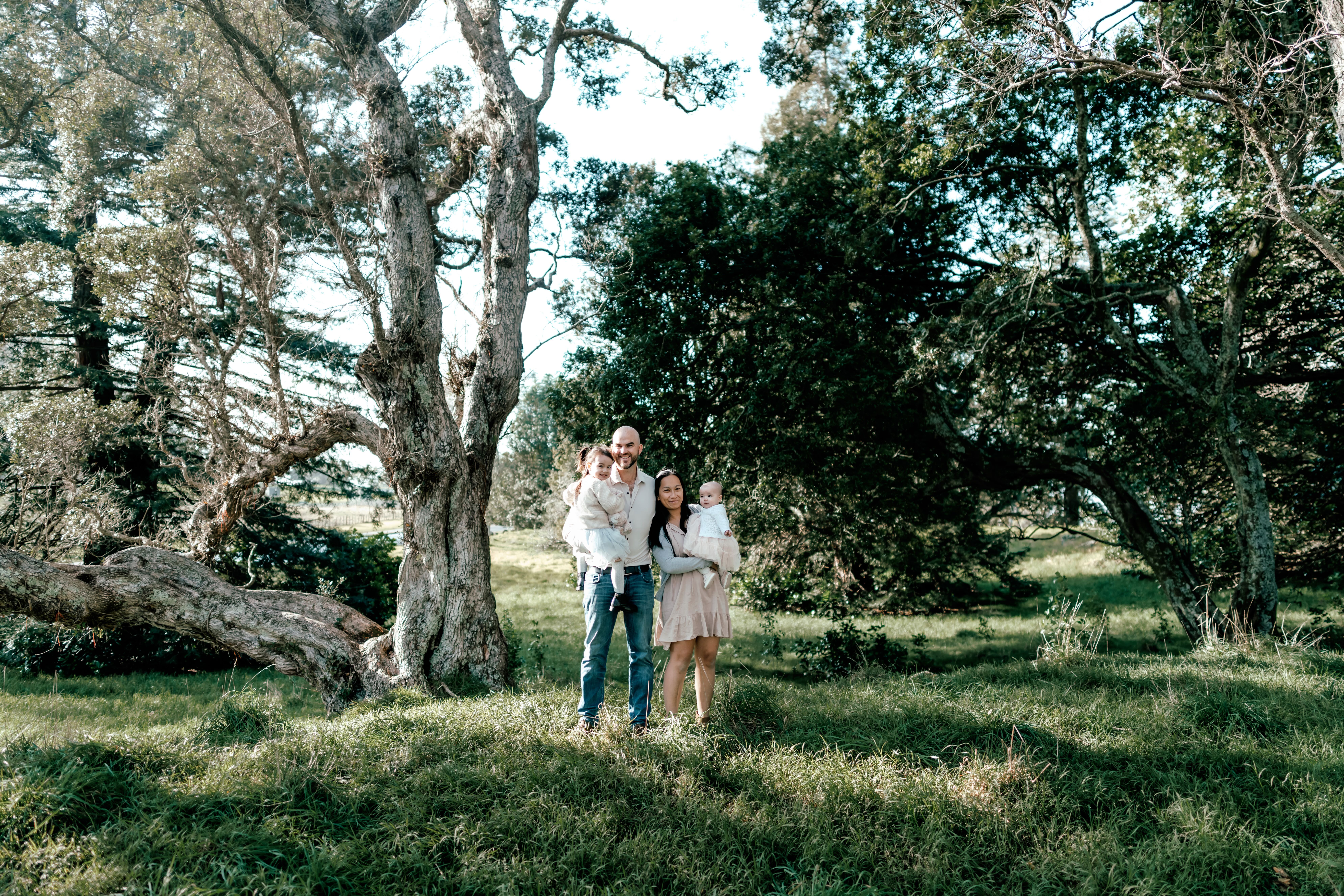 The Lam family of four in soft beige and white outfits during an outdoor family mini session at One Tree Hill in Auckland